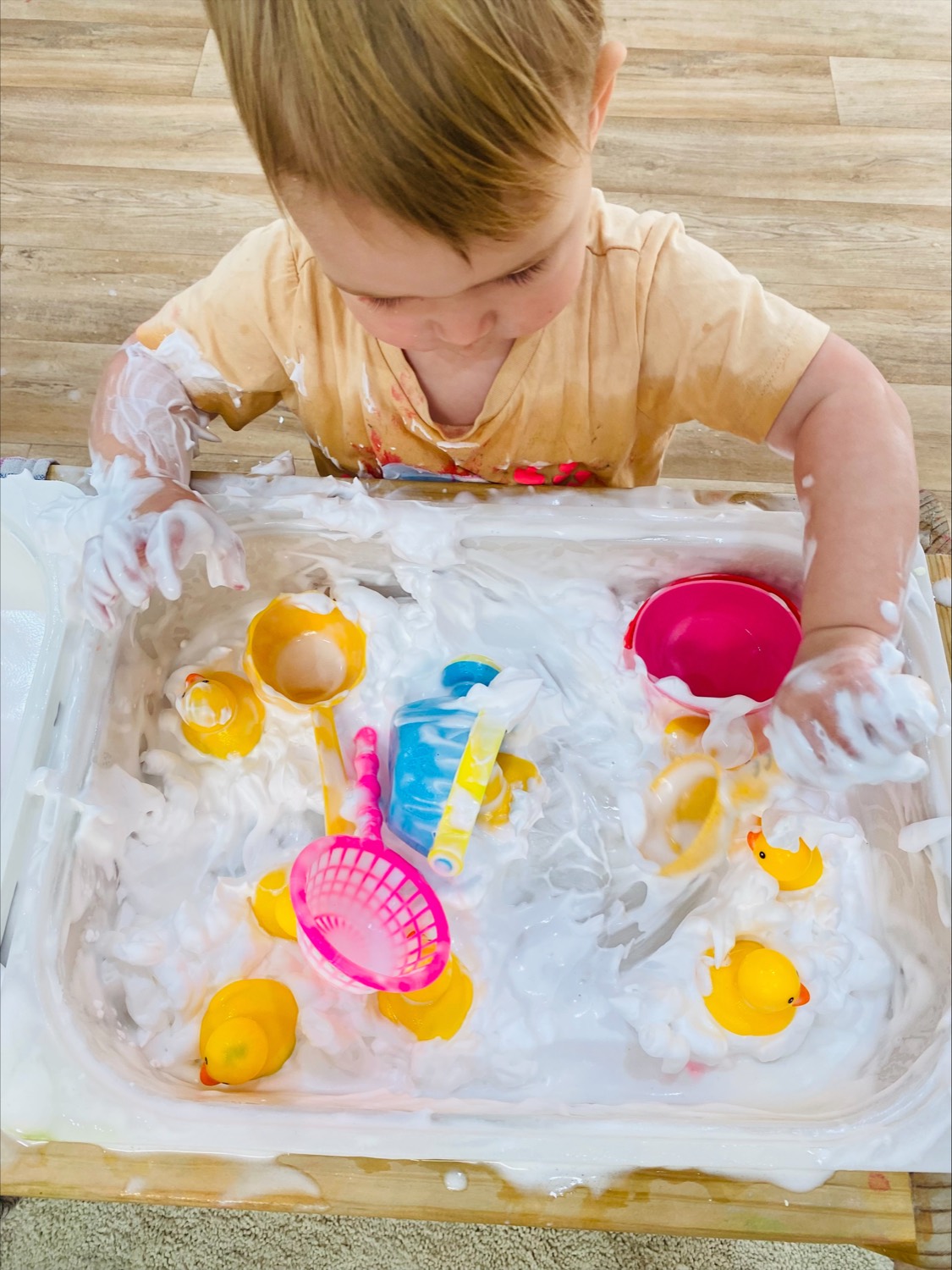 Toddler exploring a foam sensory tub at a B.Curious messy play session